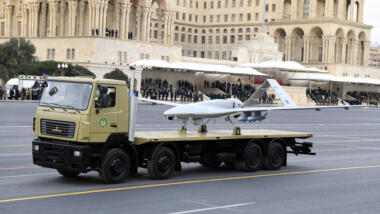 Eine türkische "Bayraktar"-Drohne wird auf einem Lastwagen durch Baku gefahren, im Hintergrund ein Regierungsgebäude.