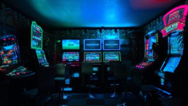 ein dunkler raum mit spielautomaten, die neonfarben leuchten.